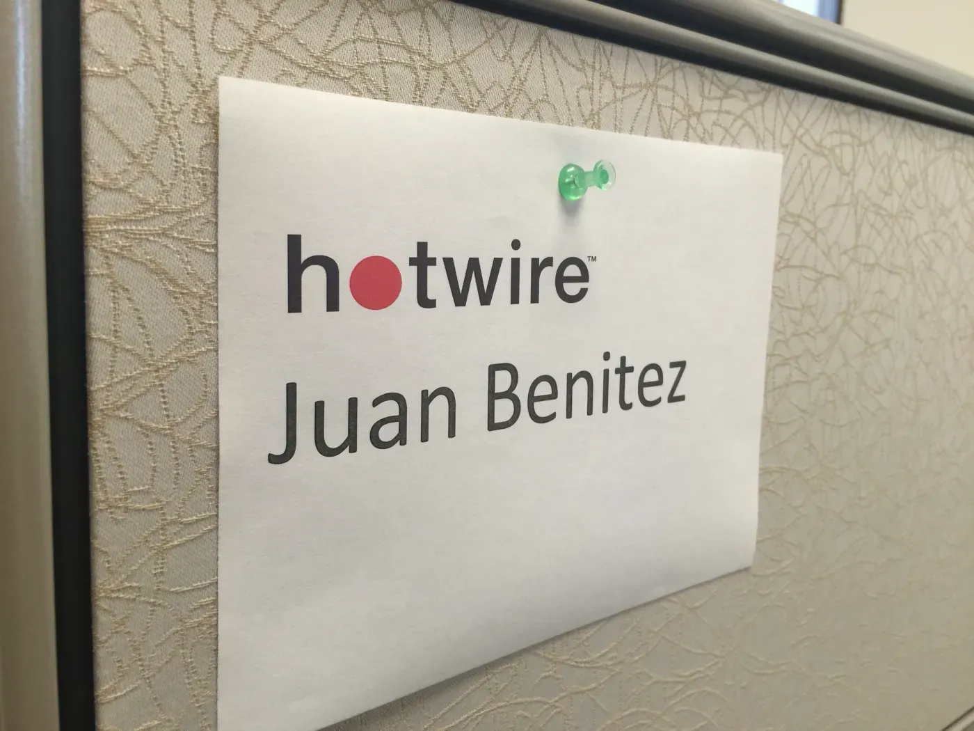 A printed Hotwire name tag pinned to a cubicle wall.